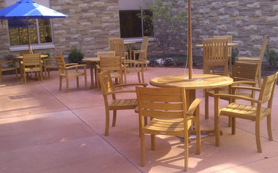 Sets of teak tables and chairs in courtyard with blue umbrella