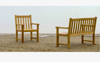 Teak bench and armchair shown on sand by the ocean