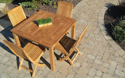 Teak dining set with square table and four chairs on brick paver patio