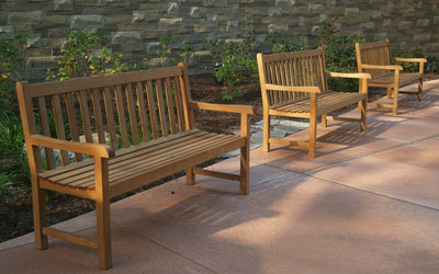 Three  teak benches lined up in front of stone wall