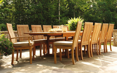 Rectangular teak table with twelve chairs shown on stone terrace