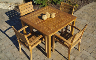 Square teak table with four chairs shown on paver patio