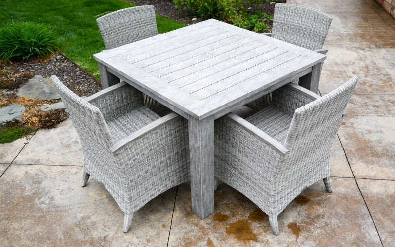 Square teak table with four woven armchairs shown on terrace