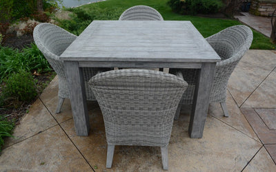 Square weathered teak table with four armchairs on stone patio