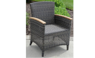 Woven armchair shown on gray patio with greenery in the background