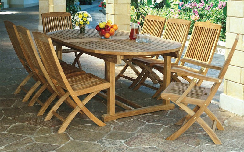 Oval teak table with eight chairs shown on a stone terrace