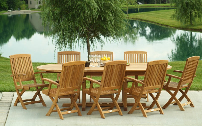 Oval teak table with eight matching armchairs by a pond