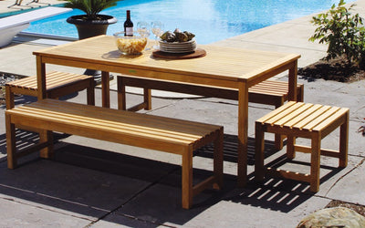 Teak dining set with table, benches and footstools by a pool