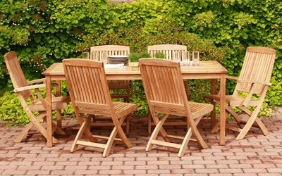 Teak dining set with rectangular table and six chairs on a brick patio
