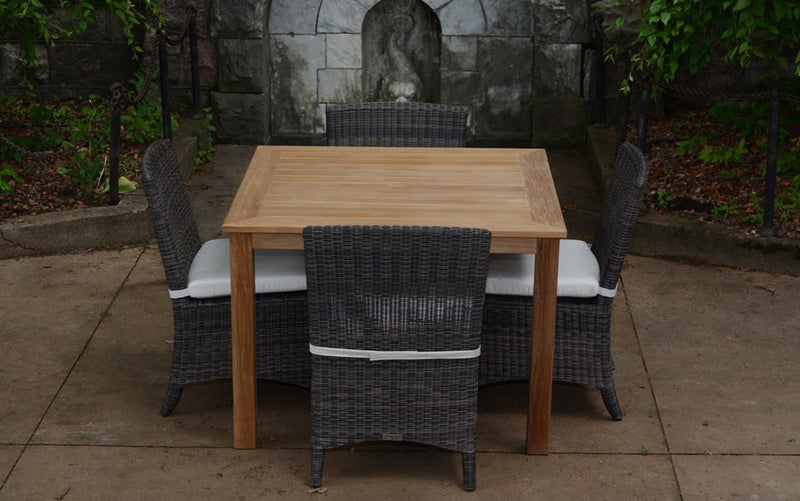 Square teak table with four brown woven chairs shown on beige terrace