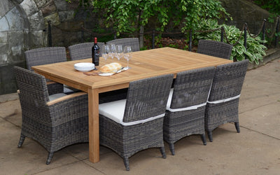 Rectangular teak table with eight woven chairs shown on light brown terrace