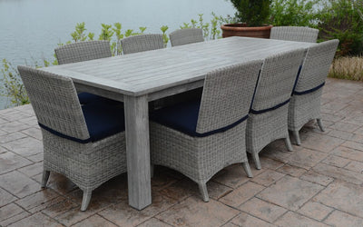 Gray teak  rectangular table with eight chairs shown on beige terrace by the water's edge