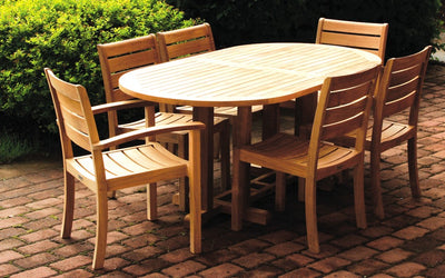 Oval teak table with six teak chairs shown on brick patio