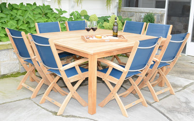 Teak table with blue chairs shown on grey patio