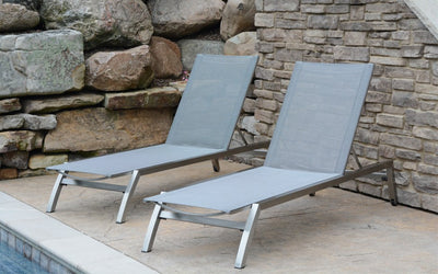 Two grey sunbeds against a rock wall